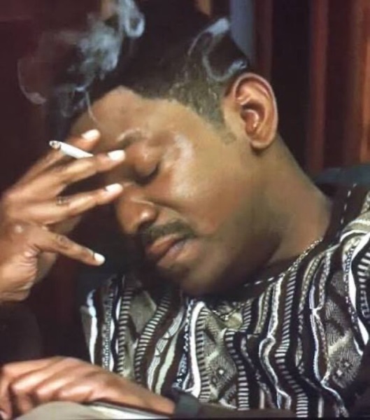 Stressed Mekhi Phifer Smoking un homme assis, les yeux fermés, la main qui tient une cigarette posée sur le front