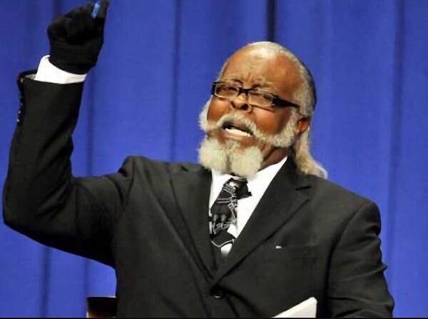 un homme à la barbe blanche et aux gants noirs, le poing levé